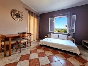 a bedroom with a bed and a table and a clock at Maspali Apartments in Lixouri