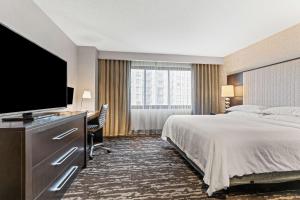 a hotel room with a bed and a flat screen tv at Embassy Suites by Hilton Crystal City National Airport in Arlington
