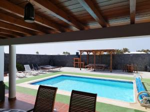 a swimming pool in a house with chairs and a table at CASA MONTES in Playa Blanca
