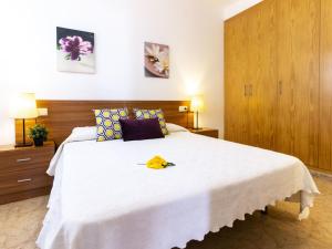 ein Schlafzimmer mit einem weißen Bett mit einer gelben Blume darauf in der Unterkunft Holiday Home Flamenc 3 by Interhome in Riumar