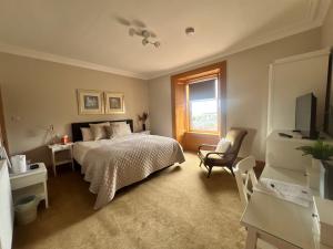 a bedroom with a bed and a chair and a window at Morven Guest House Carnoustie in Carnoustie