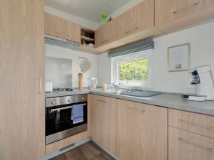 a kitchen with wooden cabinets and a stove and a window at Holiday Home Tiny Haus Altmühlblick Nr- 83 by Interhome in Beilngries