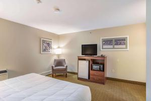 a hotel room with a bed and a tv and a chair at Quality Inn & Suites Gorham Riverside in Gorham