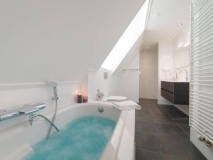 a bathroom with a bath tub with blue water at Holiday Home Ganuenta-1 by Interhome in Colijnsplaat