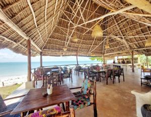 パジェにあるJaribu Beach Hotelの海とテーブルと椅子が備わるレストラン