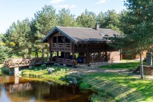 a log cabin with a bridge over a river at Vosylių kaimo turizmo sodyba in Kazlų Rūda