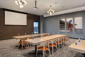 a conference room with tables and chairs and a projection screen at Tempo By Hilton Louisville Downtown Nulu in Louisville