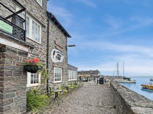a stone building with tables and chairs next to the water at Harbour House Holiday Home in Porlock