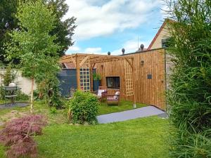a backyard with a wooden shed with a patio at Au champ du coq in Sepmeries