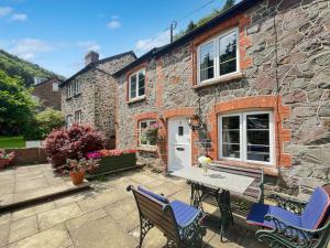 a stone house with two chairs and a table at Magnolia Cottage in Porlock