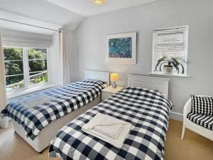 two beds in a room with two windows at Magnolia Cottage in Porlock