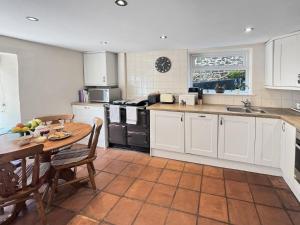 a kitchen with white cabinets and a wooden table and a table and chairs at Magnolia Cottage in Porlock