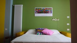 a green room with a bed with a pink pillow at Pop House - Monza Park in Villasanta