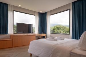 a bedroom with a large bed and a flat screen tv at The Willoughby Maerim Hotel in Chiang Mai