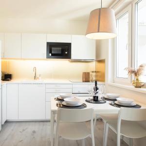 a kitchen with white cabinets and a table and chairs at Loomená Apartments - Free Garage in Košice