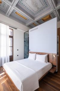 een slaapkamer met een groot wit bed en een schuin plafond bij Bouquet Luxury Rooms in Chania