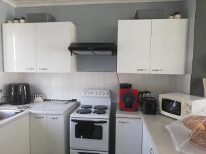 a kitchen with white cabinets and a white stove top oven at Nagua bay in Gordonʼs Bay +26 photos