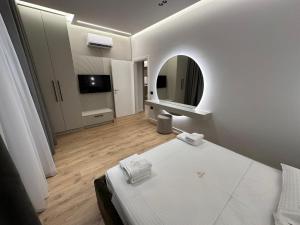 a white bedroom with a bed and a mirror at Villa MARTO in Sarandë