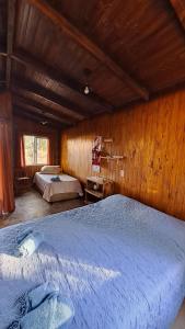 a bedroom with two beds and a wooden wall at Cabañas Bruma de Monte in El Soberbio