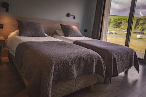 two beds in a bedroom with a window at Hótel Kría in Vík