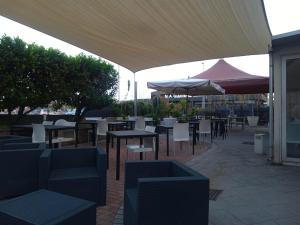 a patio with tables and chairs and an umbrella at Foresteria Diamond in Villa Pedergnano