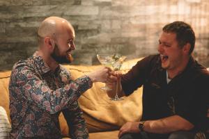 two men are holding up a martini glass at Hótel Kría in Vík
