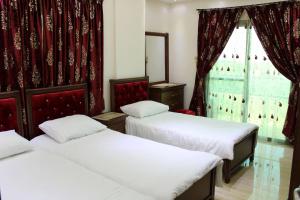 una stanza con tre letti e una finestra di Rawan Residence Tyros 