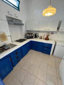 a kitchen with blue cabinets and white tile floors at Casa de Hollanda in Sidi Ifni +17 photos