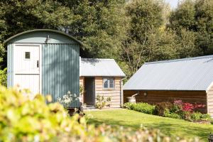 a barn with a white door and a wooden building at Shepherd's Hut at High Gardens in Hereford