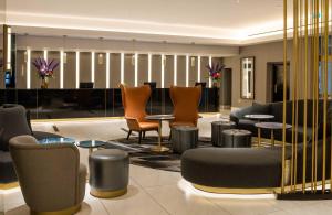 a lobby with chairs and tables and a piano at Strand Palace in London