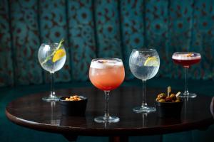 four wine glasses sitting on a wooden table at Strand Palace in London