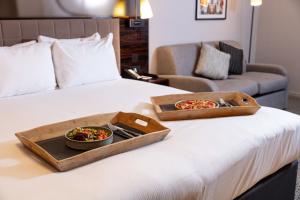 a tray of food on a bed with a plate of pizza at Strand Palace in London