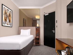 a hotel room with a bed and a television at Strand Palace in London