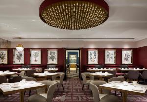 a restaurant with tables and chairs and a large chandelier at Strand Palace in London