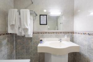 un bagno bianco con lavandino e specchio di The Harbour Inn a Buncrana