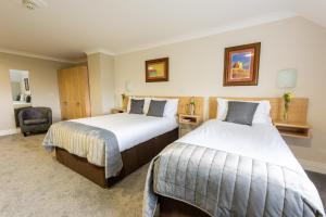 una camera d'albergo con due letti e una sedia di The Harbour Inn a Buncrana