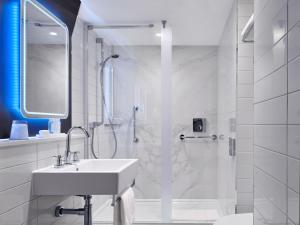 a white bathroom with a sink and a shower at Strand Palace in London