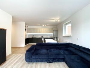 a living room with a blue couch in front of a kitchen at Apartament Warneńczyka Mielec in Mielec