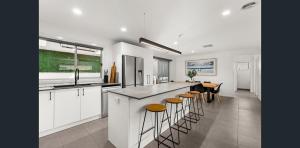 una cocina con armarios blancos y un bar con taburetes en City and Sea Retreat - Family Friendly Stay, en Marshalltown