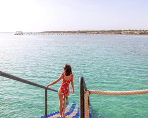 沙姆沙伊赫Pickalbatros Laguna Vista Aqua Park - 24 HRS All Inclusive的站在水面上的一个红色连衣裙的女人