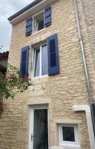 a building with blue shutters on it at Maison cosy in Mauzé-sur-le-Mignon