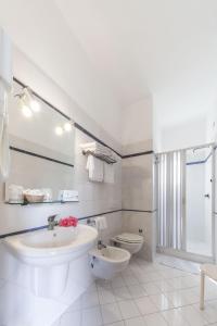 a white bathroom with a sink and a toilet at Hotel Conti in Vulcano