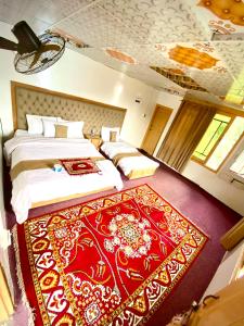 a bedroom with two beds and a red rug at Habib Green Cottage in Upper Neelun