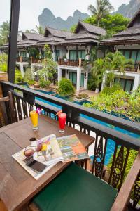a table with a book and drinks on a balcony at Railay Village Resort in Railay Beach