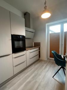 a kitchen with white cabinets and a tv and a chair at Lisboa: Messe-/Business-/Ferienwohnung in Hilden