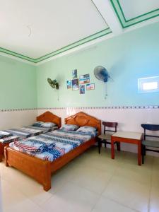 a bedroom with two beds and a table in it at Nhà Nghỉ Mỹ Châu Lý Sơn in Ly Son