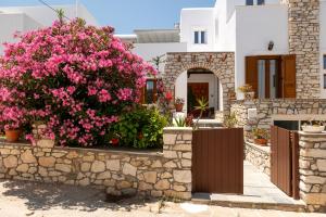 a house with pink flowers on a stone wall at ALTHEA PAROS in Naousa