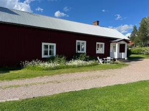 a red barn with white windows and a table in front of it at Oleby Källbacken in Torsby