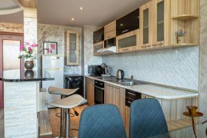 a kitchen with wooden cabinets and blue chairs at Apartments Rosina in Plovdiv