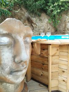 a statue of a head sitting next to a table with wine glasses at Mankao in Les Trois-Îlets